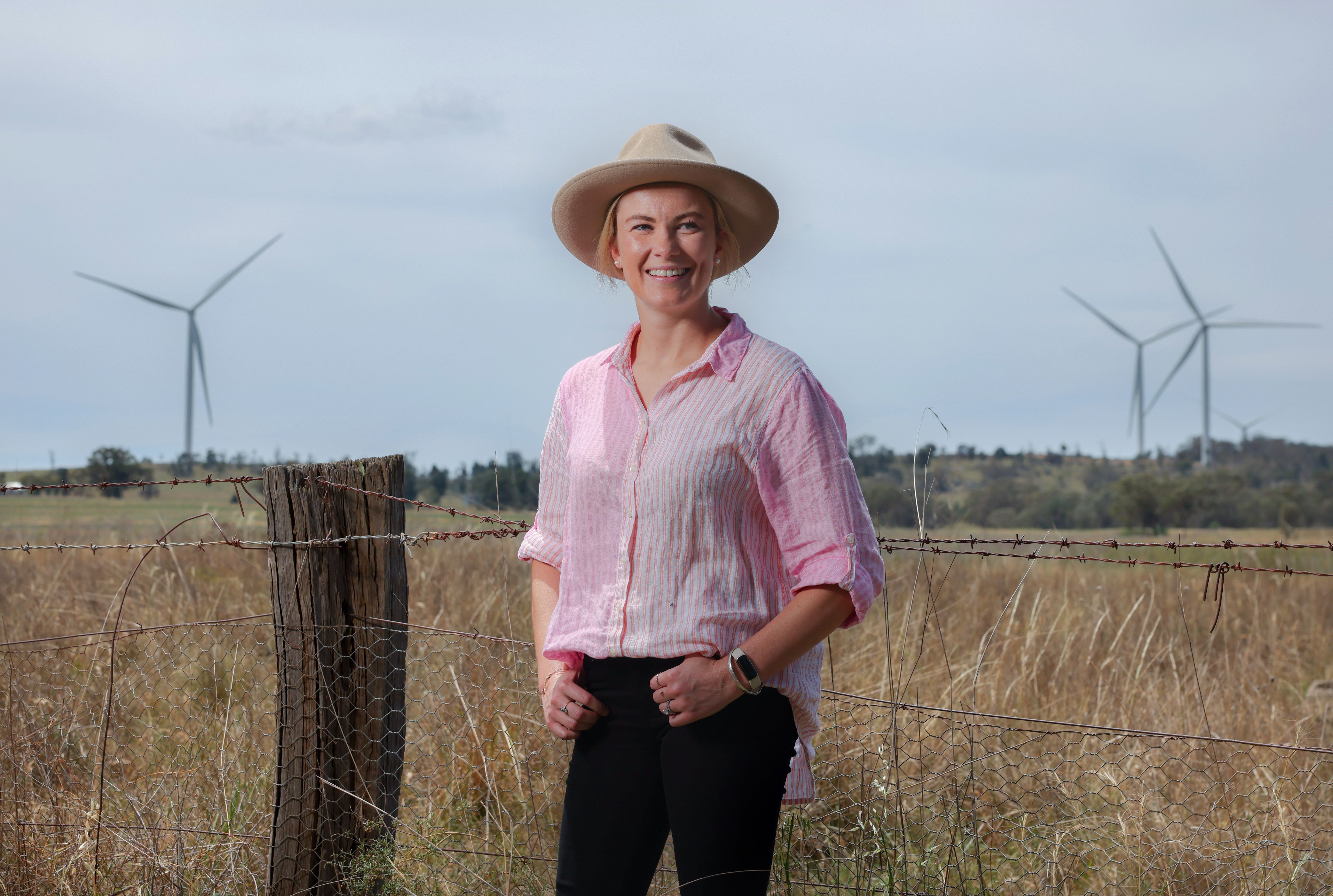 Image of a young blonde woman in a field wearing a pink shirt and hat